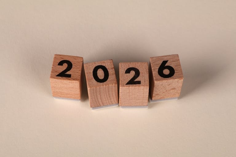 Wooden cubes forming the year 2026 on a neutral background.